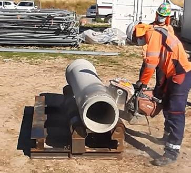 Compagnon en train de découper un tuyau de gros diamètre sur la table adaptée pour cette opération